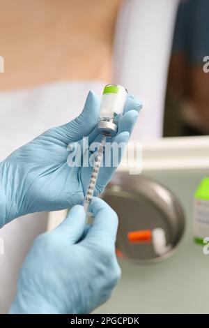 Seringue dans les mains d'un esthéticien. Cosmétologie esthétique. Mains en gants bleus et une seringue avec une préparation médicale. injections de beauté. Botox. Banque D'Images
