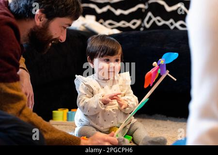 Homme heureux dans des vêtements décontractés assis sur le sol et jouant avec la petite fille tout en passant du temps à la maison ensemble Banque D'Images