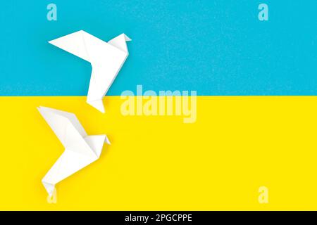 Deux feuilles de papier blanc origami sont gravées sur les couleurs du drapeau de l'Ukraine. Le concept de paix entre deux États. Symbole de paix sur fond bleu et jaune. Po Banque D'Images