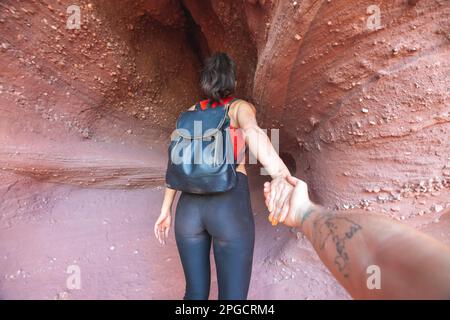 Vue arrière d'une touriste féminine avec sac à dos tenant les mains avec un crop-man tatoué tout en marchant dans le Red Canyon Banque D'Images