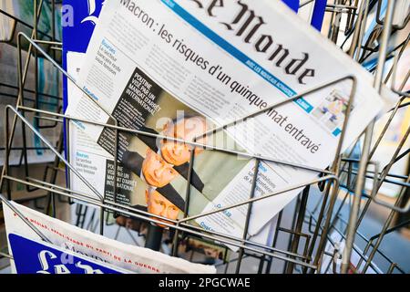 Paris, France - 20 mars 2023 : vue à travers les barres d'acier sécurisées d'un détenteur de kiosque de presse, portraits multiples du président russe poutine avec un titre visé par un mandat d'arrêt international sur une couverture de journal français le monde avec des piétons en arrière-plan Banque D'Images
