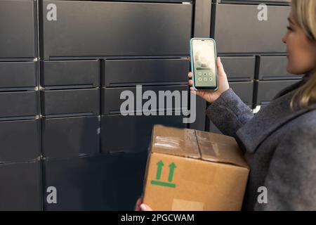 Belle femme ramassant un paquet d'un casier électronique intelligent en acier de colis, boîtes automatiques. Paczkomat service de livraison, collection Banque D'Images