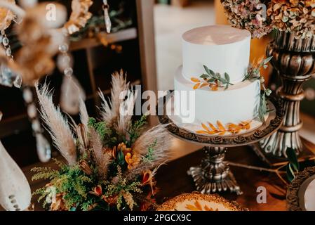 Image d'une cérémonie de mariage à l'intérieur, avec un gâteau blanc à trois niveaux décoré de fleurs comme pièce maîtresse Banque D'Images