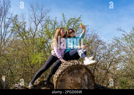 couple de femmes très amicales prenant un selfie avec smartphone assis sur pile de billes à l'extérieur Banque D'Images