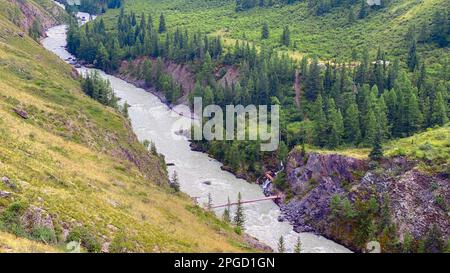 L'étroite rivière Chuya dans les canyons entre les montagnes coule avec un petit pont sur l'Altaï en Sibérie pendant la journée. Banque D'Images