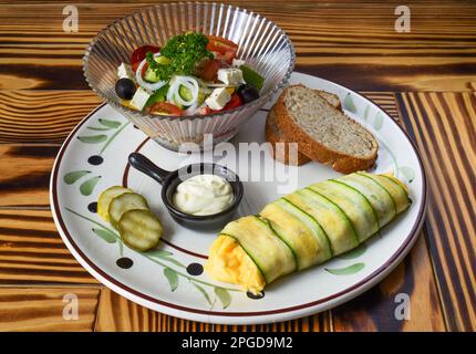 Omelette de courgettes avec salade fraîche, pain et sauce sur une assiette sur une table en bois Banque D'Images