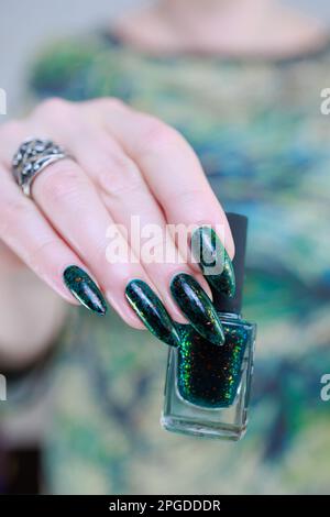 Main de femme avec de longs ongles et vernis à ongles vert foncé Banque D'Images