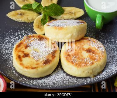 Crêpes au sirop ou au fromage avec sauce à la crème et bananes sur une assiette sur une table en bois Banque D'Images