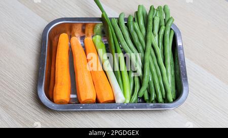 tranchez les carottes, la ciboulette et les haricots verts dans un bol Banque D'Images