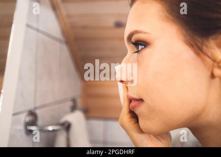 Gros plan sur le côté des femmes démaquillage à l'aide d'un tampon en coton Banque D'Images