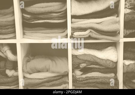 Pile de vêtements tricotés colorés - chandails, robes, cardigans etc Photo vieillie avec effet de brume. Sépia. Banque D'Images