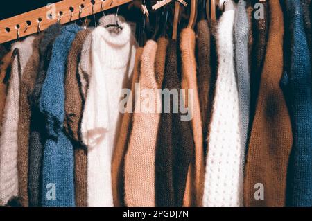 Vêtements tricotés colorés suspendus - chandails, robes, cardigans etc Photo en tons. Banque D'Images