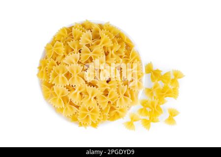 Farfalle dans un bol isolé sur fond blanc. Pâtes crues en forme de papillon, ingrédient pour cuisiner, cuisine italienne traditionnelle. Vue de dessus, plan d'agencement Banque D'Images