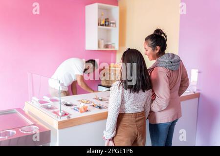 Une jeune femme et sa sœur font un choix de tête dans une glacerie Banque D'Images