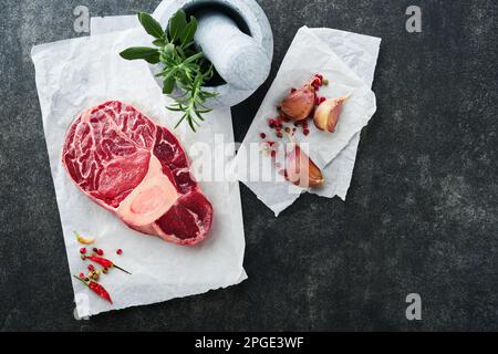 Steak de viande cru Osso Buco. Viande de barbecue. Jarret de veau frais coupé en croix et assaisonnements poivre, romarin, thym et sel sur fond sombre. Bœuf S Banque D'Images