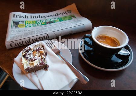 Tasse d'espresso fraîchement préparé dans le journal Irish Independent. Table en bois. Banque D'Images