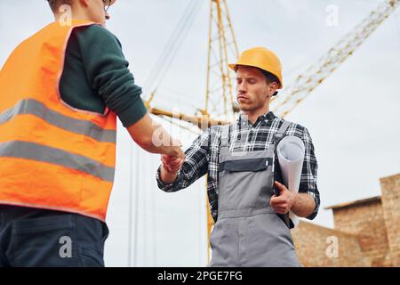 Faire une poignée de main. Deux ouvriers de la construction en uniforme ...
