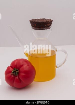 Huile d'olive dans une bouteille de verre et tomate sur fond blanc isolé. Une alimentation saine. Banque D'Images