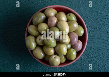 Bol rempli d'olives vertes sur fond vert Banque D'Images