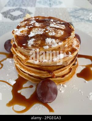 Une assiette blanche avec une multitude de crêpes moelleuses nappées d'une délicieuse sauce Banque D'Images