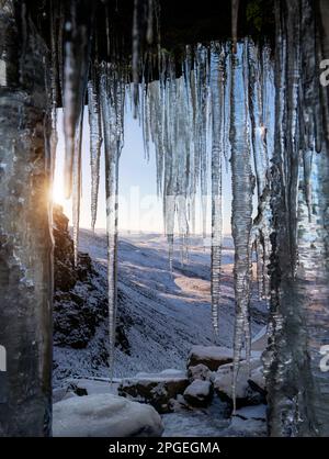 Devant la chute d'eau de Kinder surgelée, la neige couverte, paysage d'hiver du quartier de pic anglais encadré par Icicles. Sur Kinder Scout. Banque D'Images