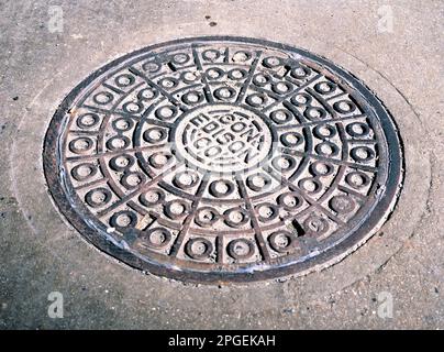 NEW YORK,USA-19 mars 2023: Trou d'homme avec couverture métallique dans une surface asphaltée fissurée dans une rue de la ville de New York. Banque D'Images