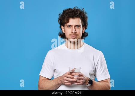 homme en t-shirt blanc tenant un verre d'eau potable Banque D'Images