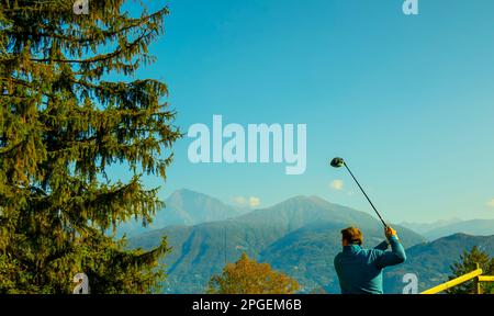 Golfeur Tearing off avec son chauffeur sur le terrain de golf Menaggio avec vue sur la montagne en automne dans Lombardie, Italie. Banque D'Images