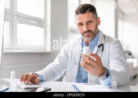 Homme médecin médecin médecin médecin médecin assis à la table de travail, tenant un pot de pilules et écrivant la prescription sur une forme spéciale Banque D'Images