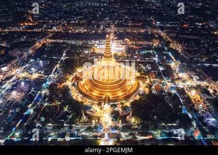 Vue aérienne de la pagode dorée Majestic de Phra Pathom Chedi, qui brille parmi les lumières du festival autour de la route du rond-point dans le centre-ville de Nakhon Pathom, Banque D'Images