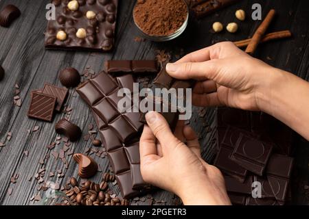 Assiette de chocolat sur fond de bois sombre. Dessert au chocolat entre les mains des femmes sur fond de chocolat noir et de chocolat au lait. Banque D'Images