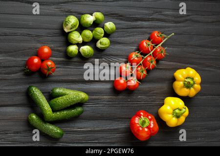 Concombres frais, tomates cerises, poivrons colorés, choux de bruxelles sur fond de bois sombre vue du dessus. Légumes crus. Une alimentation adéquate. Banque D'Images