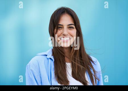 Portrait jeune belle femme souriante regardant caméra ciel bleu arrière-plan. Bonne fille. Banque D'Images