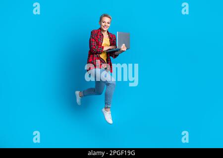 Pleine taille photo cadre de jeune perspective programmeur junior codeur femme étudiant tenir netbook saut isolé sur fond bleu de couleur Banque D'Images