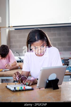 Vertical Latino fille étudiant à l'école secondaire technique dans la salle de classe pièces de matériel sur les cartes de circuit imprimé. Banque D'Images