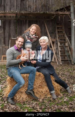 Portrait de famille avec oiseau de poulet assis dans la ferme avicole, Bavière, Allemagne Banque D'Images