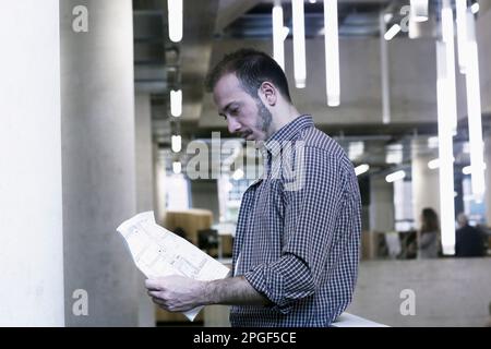 Jeune architecte regardant un plan dans un bureau, Freiburg im Breisgau, Bade-Wurtemberg, Allemagne Banque D'Images