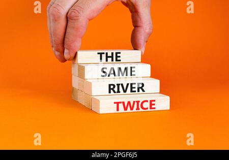 La même rivière deux fois symbole. Concept mots la même rivière deux fois sur bloc de bois. Belle table orange fond orange. Motivation des affaires les s Banque D'Images