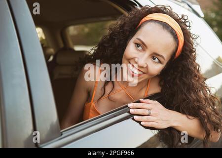 La fille regarde hors de la fenêtre de voiture et sourire Banque D'Images