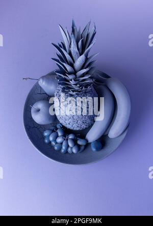 Une image encore-vie de divers fruits et d'un ananas sur une assiette, avec des teintes bleues Banque D'Images
