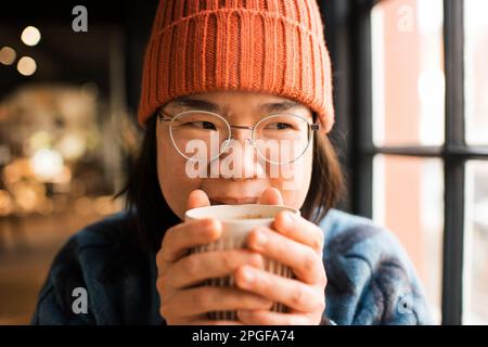 Portrait en gros plan d'une femme asiatique qui boit du café dans un café Banque D'Images