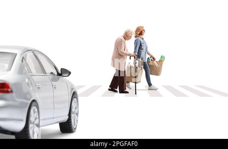 Voiture conduisant vers une traversée piétonne, une femme avec une dame âgée traversant la rue et portant des sacs d'épicerie isolés sur fond blanc Banque D'Images