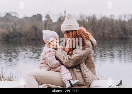 Maman et bébé maussettes sont assis dans un parc brumeux au bord de la rivière Banque D'Images