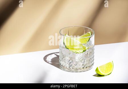 Cocktail alcoolisé TI punch avec rhum blanc, sirop de sucre et citron vert, boisson traditionnelle des Caraïbes. Arrière-plan beige, style minimaliste Banque D'Images