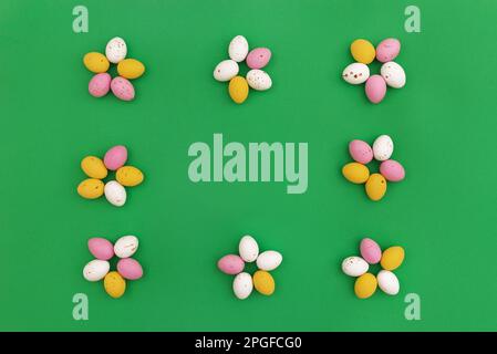 Arrière-plan de Pâques. Œufs de chocolat colorés disposés en forme de fleurs, qui forment un cadre sur fond vert. Utilisation pour la publicité de Pâques ou de printemps comme image décorative pour le site Web. Vue de dessus.Copier l'espace Banque D'Images