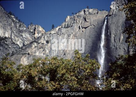 Parc national de Yosemite. ENV. ÉTATS-UNIS 1984. Yosemite Upper, Middle et Lower Falls. Repérez le cône de glace à la base de l'automne supérieur pendant l'hiver et le ruissellement torant d'avril à juin. Les chutes de Yosemite, l'une des plus hautes du monde, sont en fait composées de trois chutes distinctes : la chute de Yosemite supérieure (1 430 pieds), les cascades moyennes (675 pieds) et la chute de Yosemite inférieure (320 pieds). La meilleure observation des chutes de Yosemite est la région autour de Sentinel Meadow et de la Yosemite Chapel. Nevada Falls, Bridalveil Falls et Vernal Falls vus depuis le fond de la vallée de Yosemite. Banque D'Images