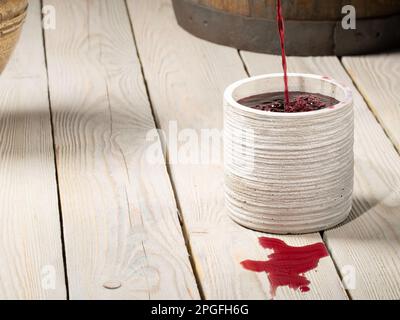 Le vin rouge est versé dans un verre de la table à partir d'un pot de terre Banque D'Images