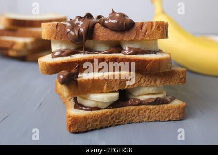 un sandwich sucré de pâte de banane et de chocolat sur un fond gris avec de l'espace pour le texte et le copyspace. Petit déjeuner délicieux en calories. Banque D'Images