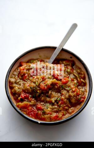 Meze d'aubergines grecques dans un bol en céramique avec une cuillère. Aubergines cuites au four avec tomates et poivrons avec ail. Banque D'Images