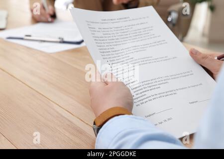 Homme lisant le contrat d'emploi à la table au bureau, clôture. Signature du contrat Banque D'Images